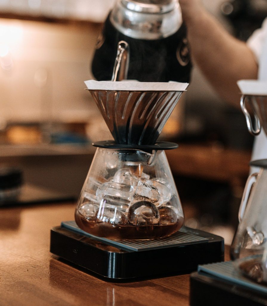 Close-up of water being poured into a coffee dripper in a cozy cafe setting.